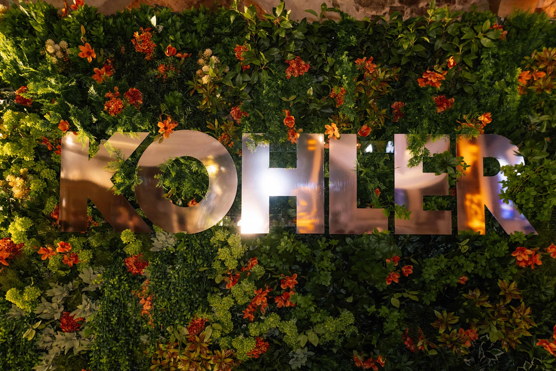 Kohler lettering set into a wall of greenery and flowers